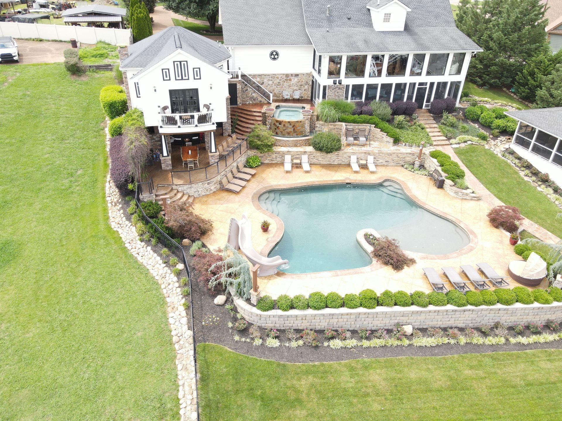 An aerial view of a large house with a large swimming pool in the backyard.