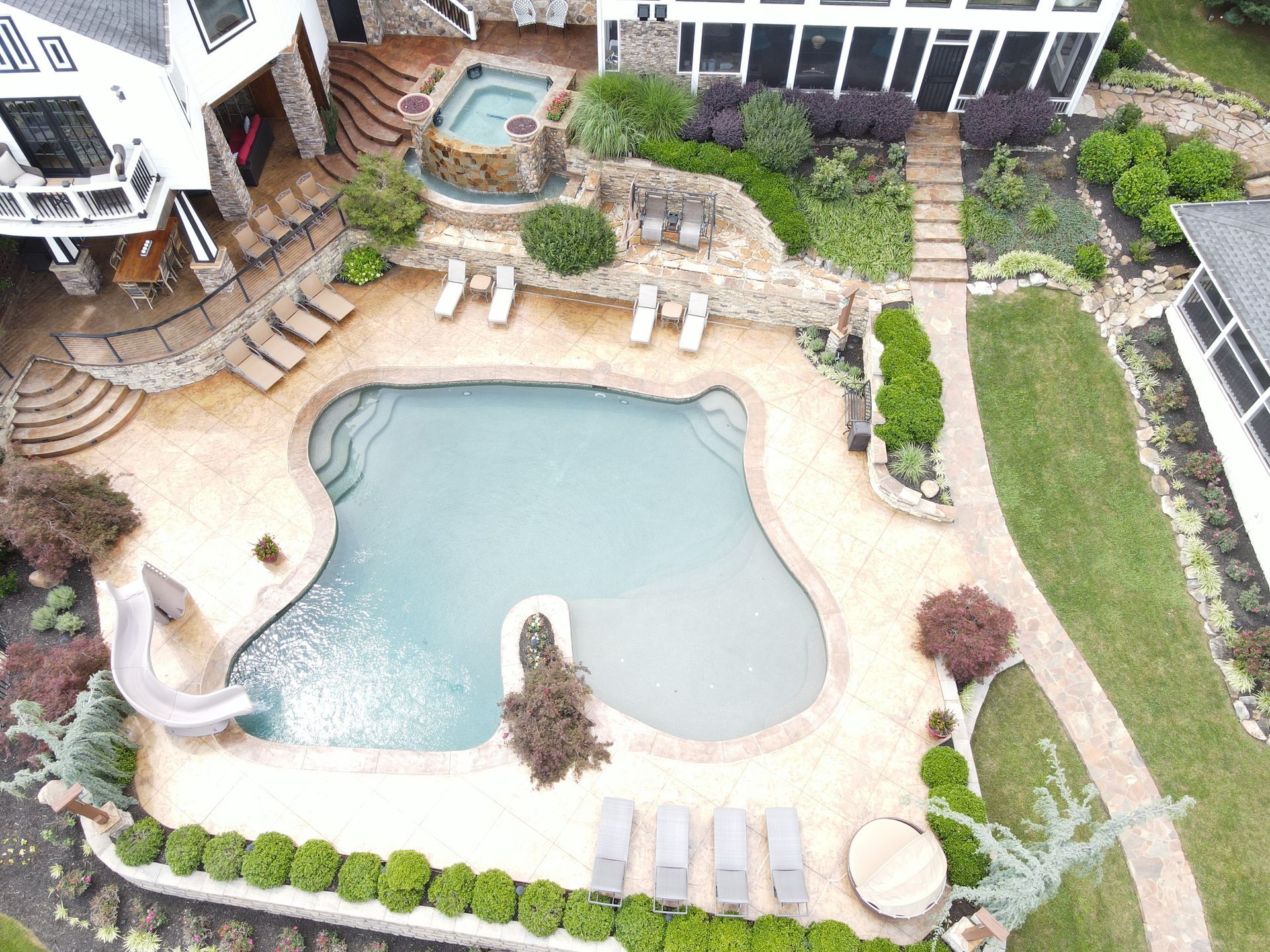 An aerial view of a large swimming pool in the backyard of a house.