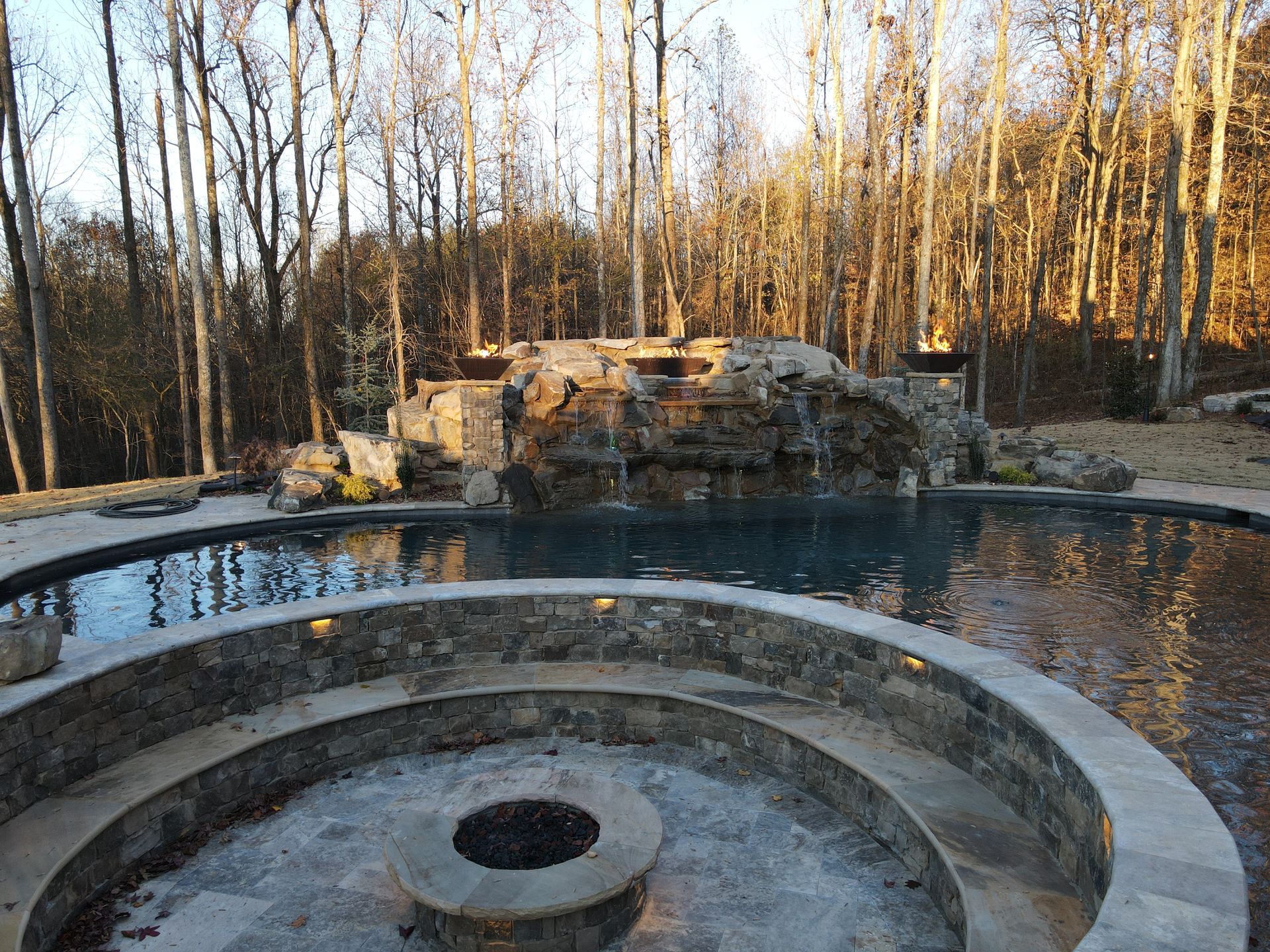 A swimming pool with a fire pit in the middle of it