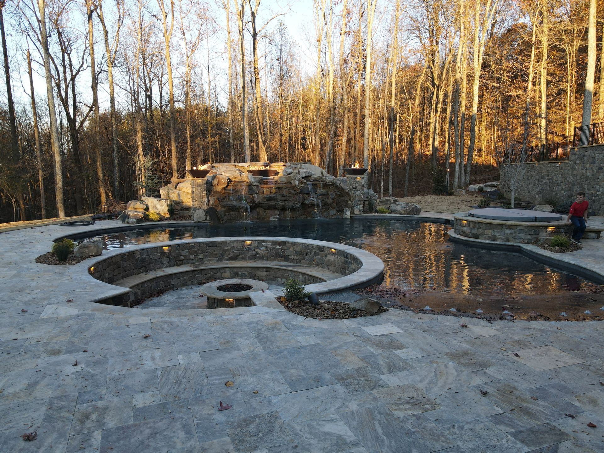 A large swimming pool in the middle of a forest surrounded by trees.