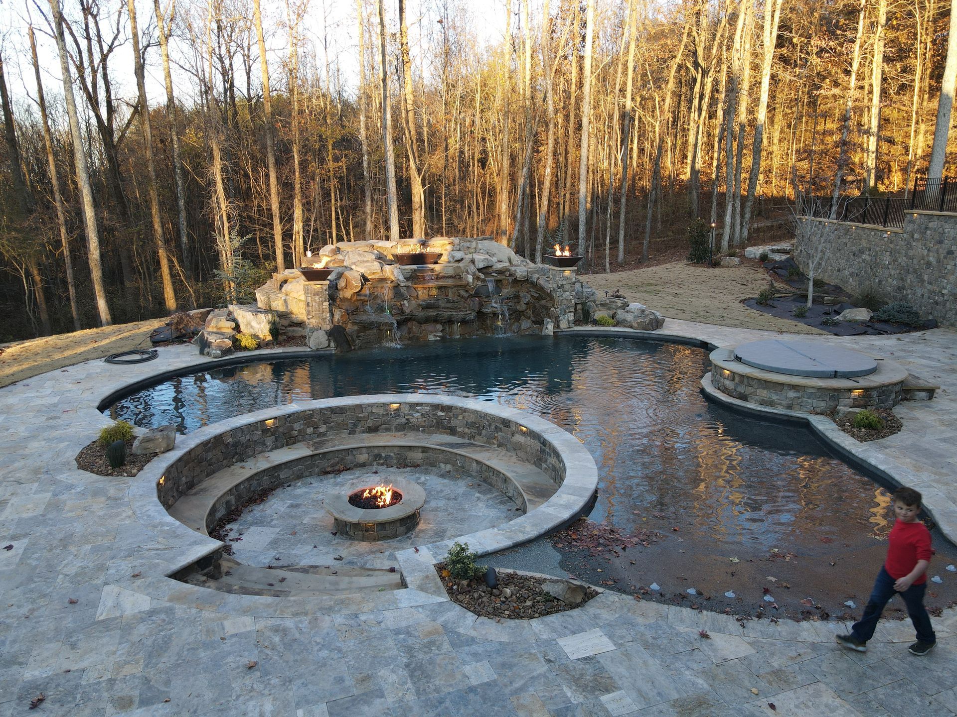 A large swimming pool with a fire pit in the middle of it