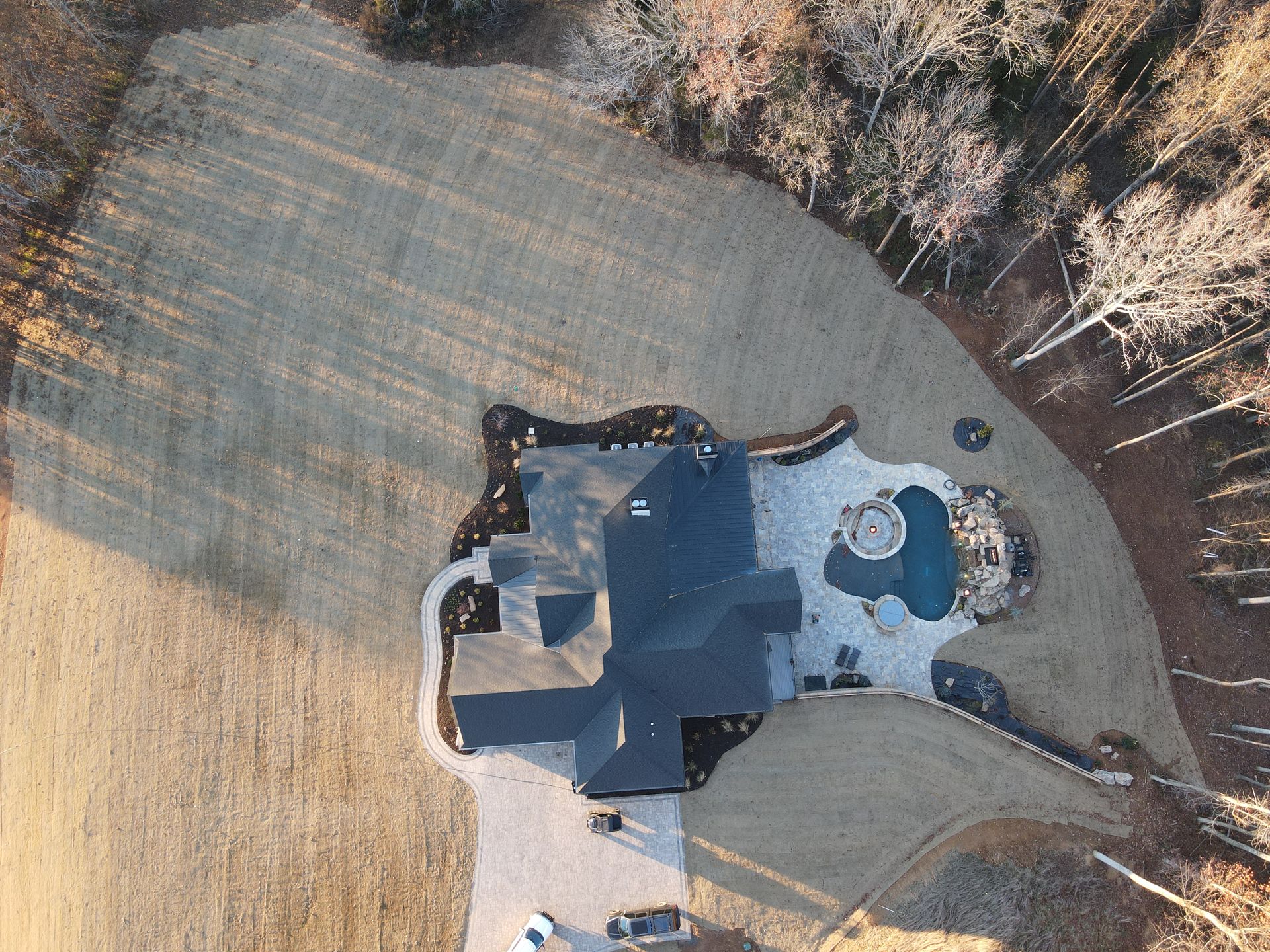 An aerial view of a house with a pool in the backyard surrounded by trees.