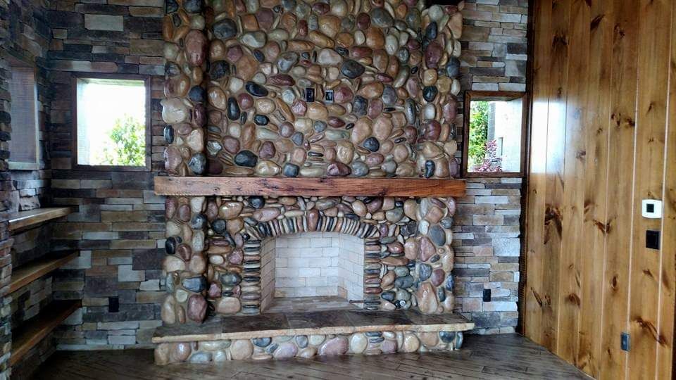 There is a stone fireplace in the middle of the room.