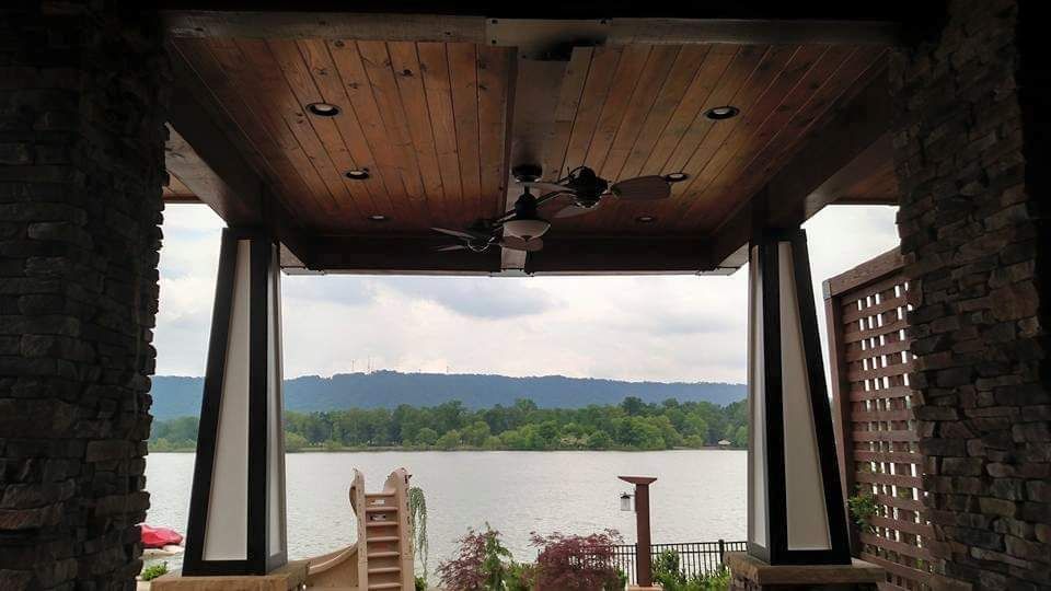 A view of a lake from a porch with a ceiling fan