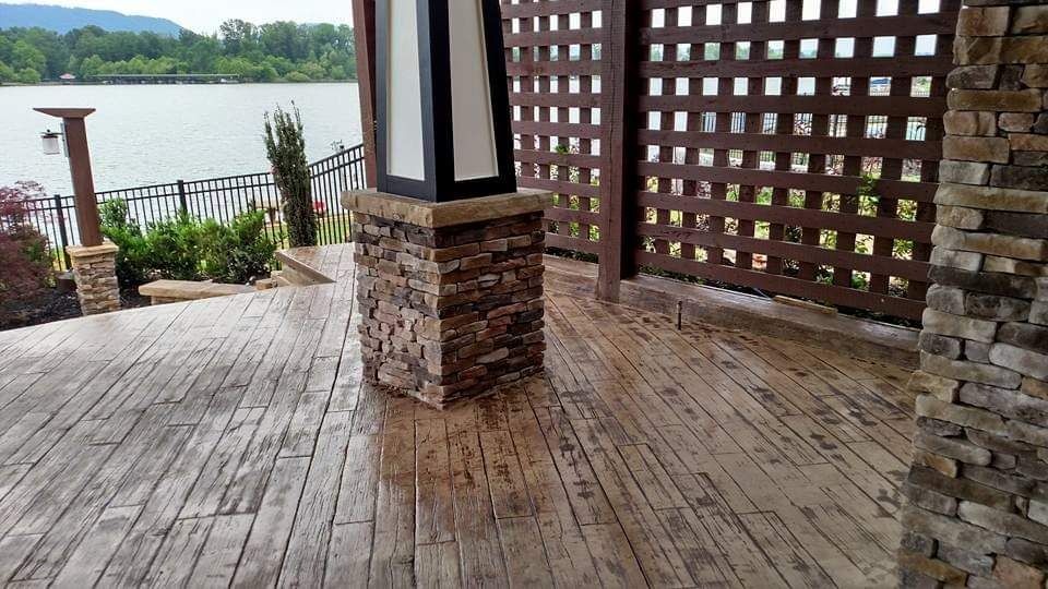 A patio with a stone wall and a view of a lake.
