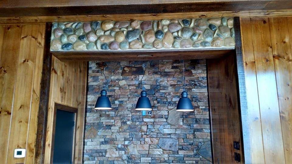 There are three lights hanging from the ceiling above a stone wall.