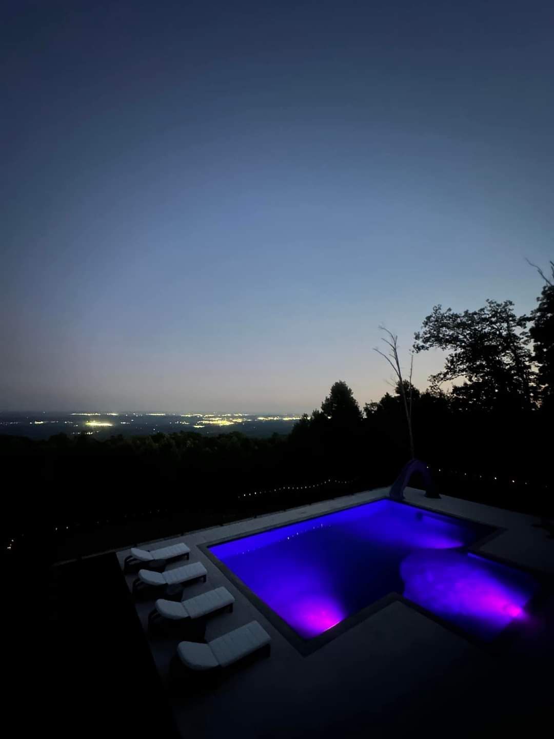 A swimming pool is lit up with purple lights at night