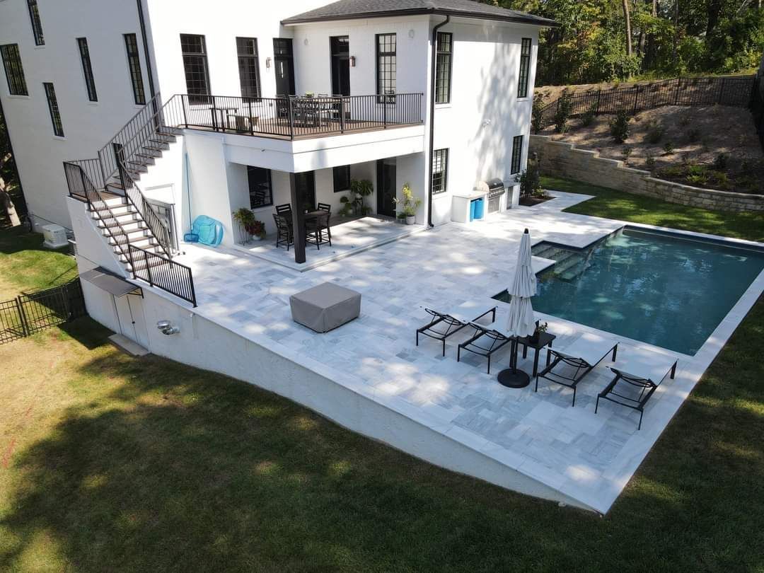 An aerial view of a large white house with a large swimming pool.