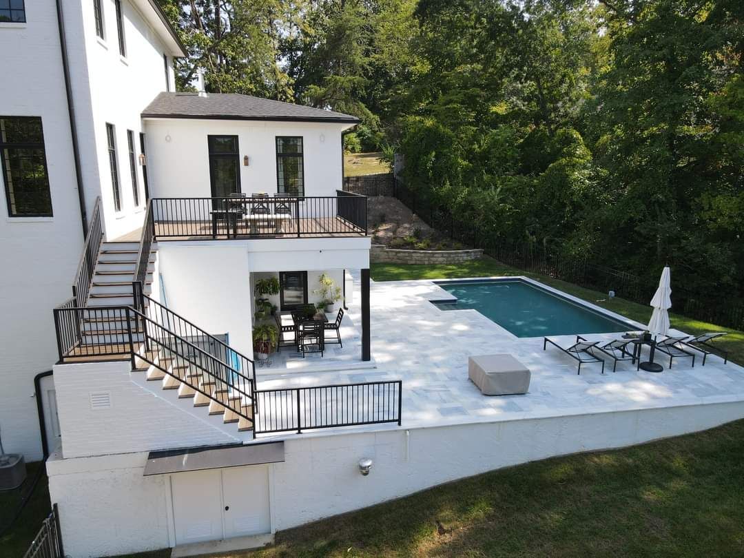 An aerial view of a white house with a large swimming pool in the backyard.