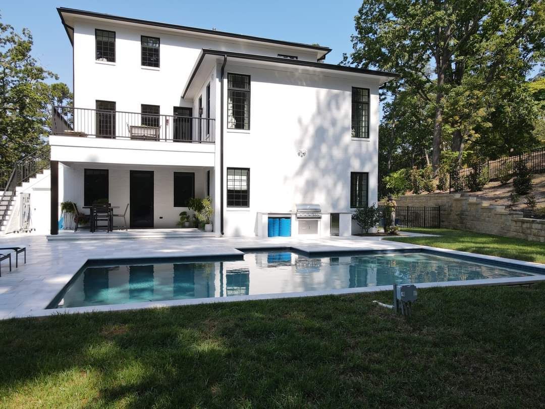 A white house with a large swimming pool in front of it