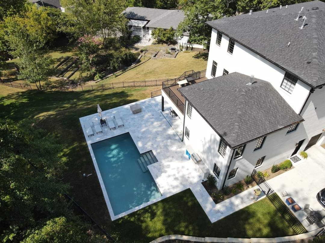 An aerial view of a house with a large swimming pool in the backyard.