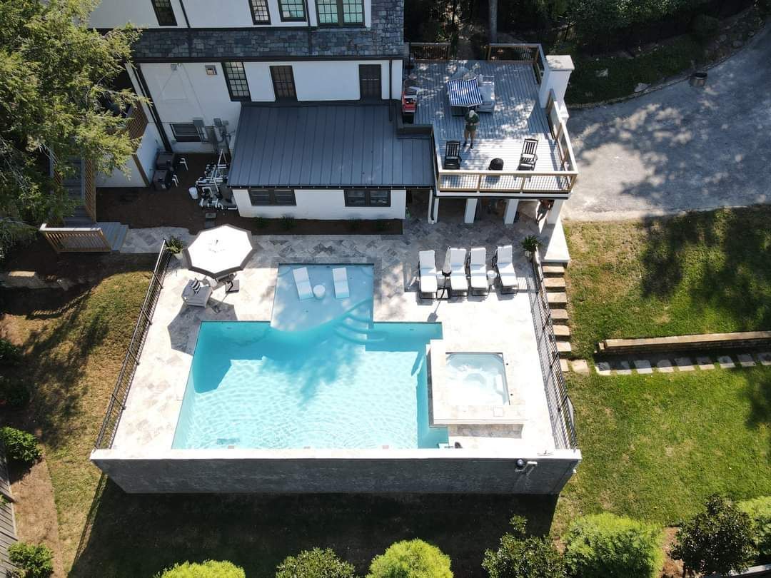 An aerial view of a large swimming pool in the backyard of a house.