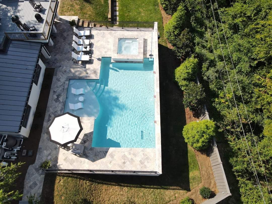 An aerial view of a large swimming pool surrounded by trees.