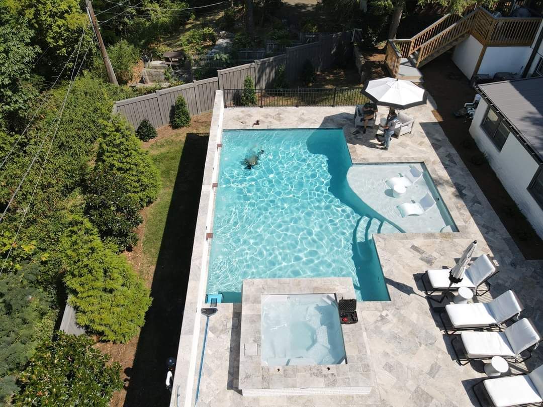 An aerial view of a large swimming pool with a hot tub