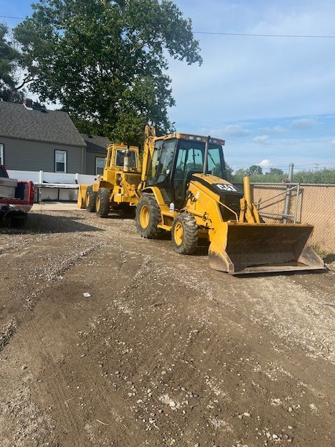 Two yellow tractors are parked on a dirt road