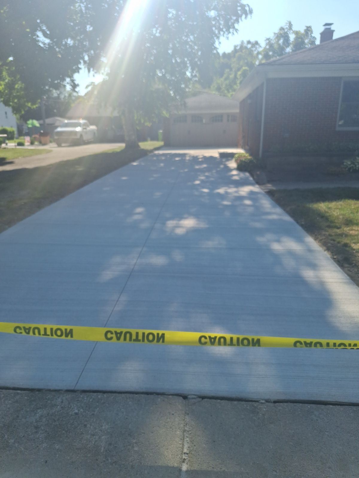 A concrete driveway with a yellow caution tape on it