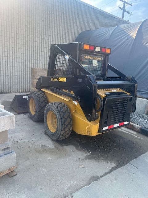A yellow and black skid steer is parked in front of a building.