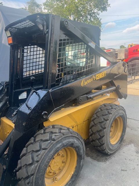 A yellow and black skid steer is parked on the side of the road.