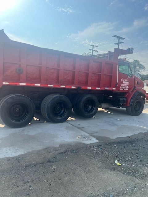 A red dump truck is parked on the side of the road.