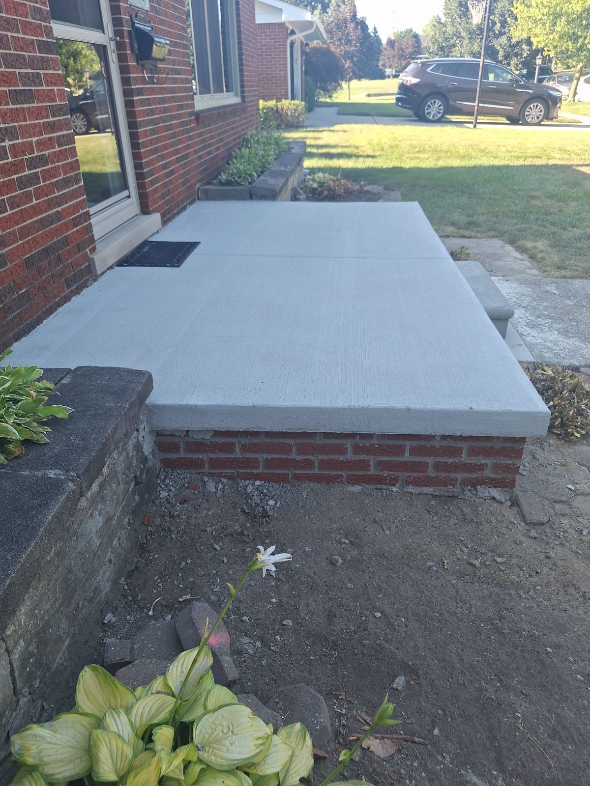 A brick house with a concrete walkway in front of it.