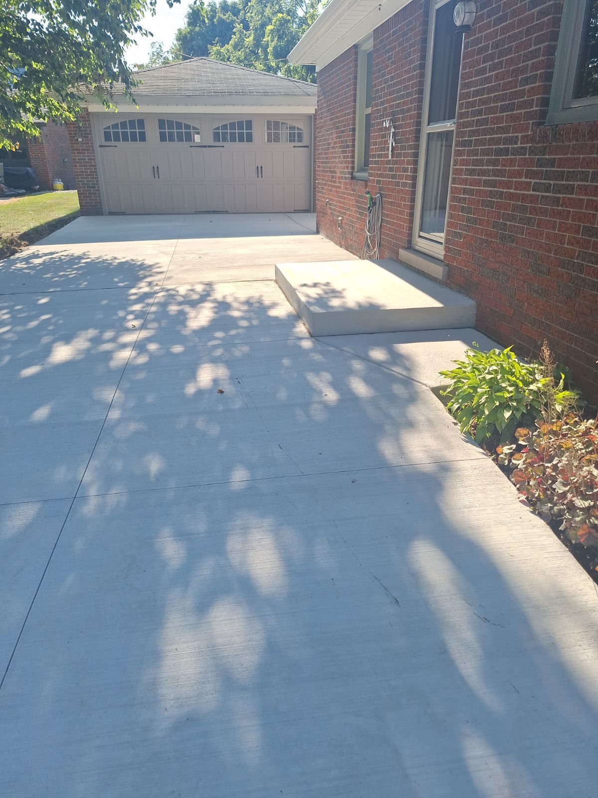 A brick house with a concrete driveway leading to it.