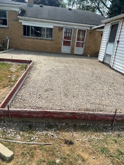 A brick house with a gravel driveway in front of it.