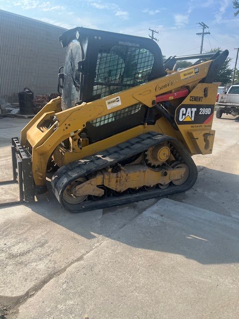 A yellow cat skid steer is parked in a parking lot.
