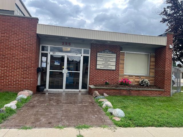The front of a brick building with a white door and windows.