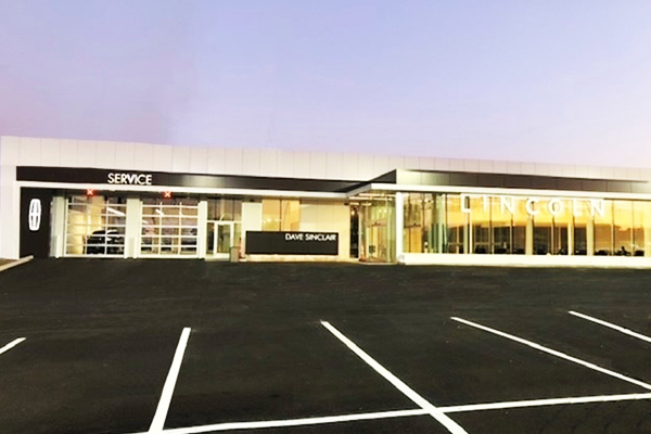 A lincoln dealership with a parking lot in front of it