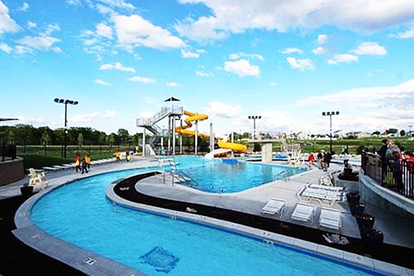 A large swimming pool with a water slide in the background.