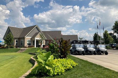 A row of golf carts are parked in front of a house.