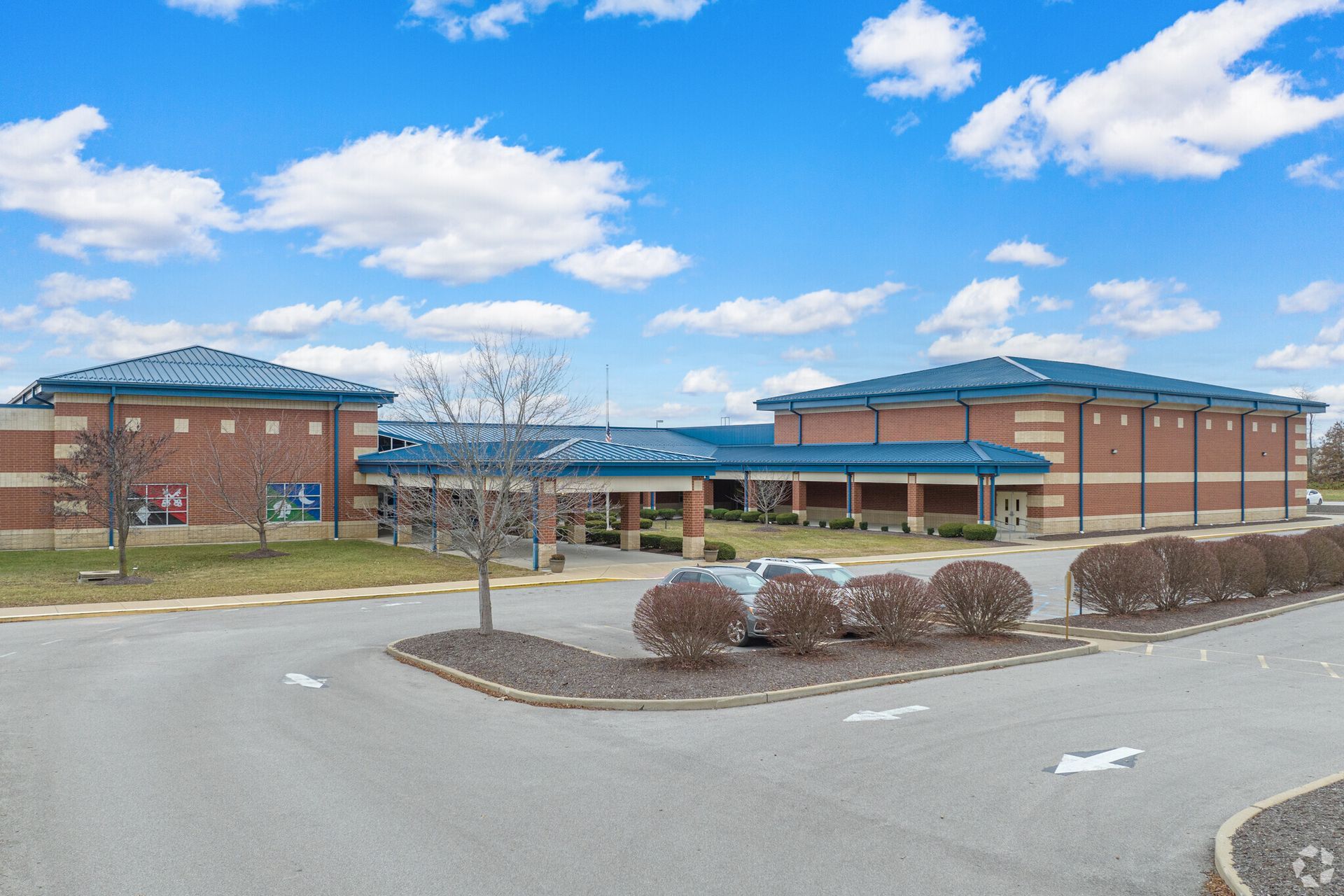 A large brick building with a blue roof and a car parked in front of it.