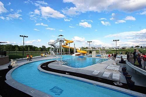 A large swimming pool with a water slide in the background.