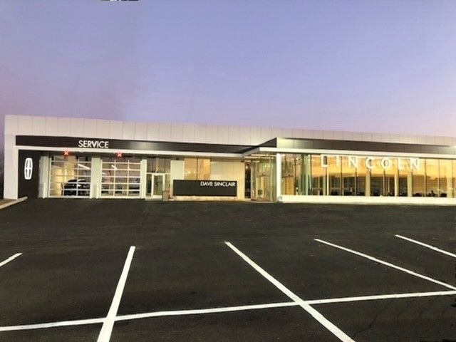 A lincoln dealership with a parking lot in front of it