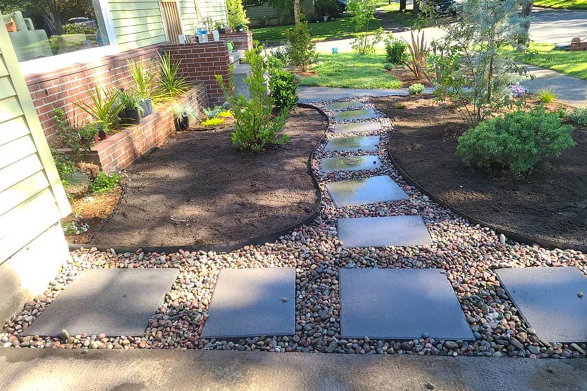 A stone walkway leading to a house with a brick wall in the background.