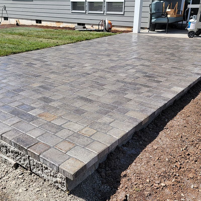 A brick patio is being built in front of a house.
