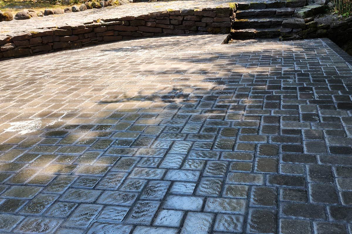 A brick walkway with stairs and a stone wall in the background.