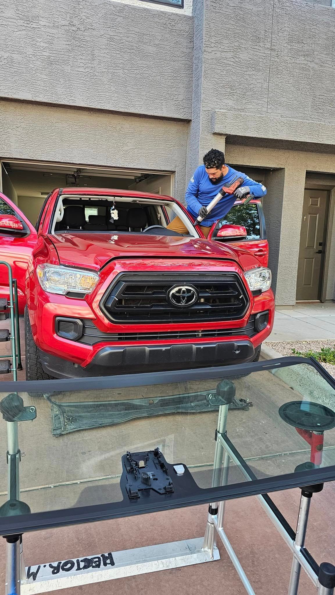 A man is installing a windshield on a red truck.