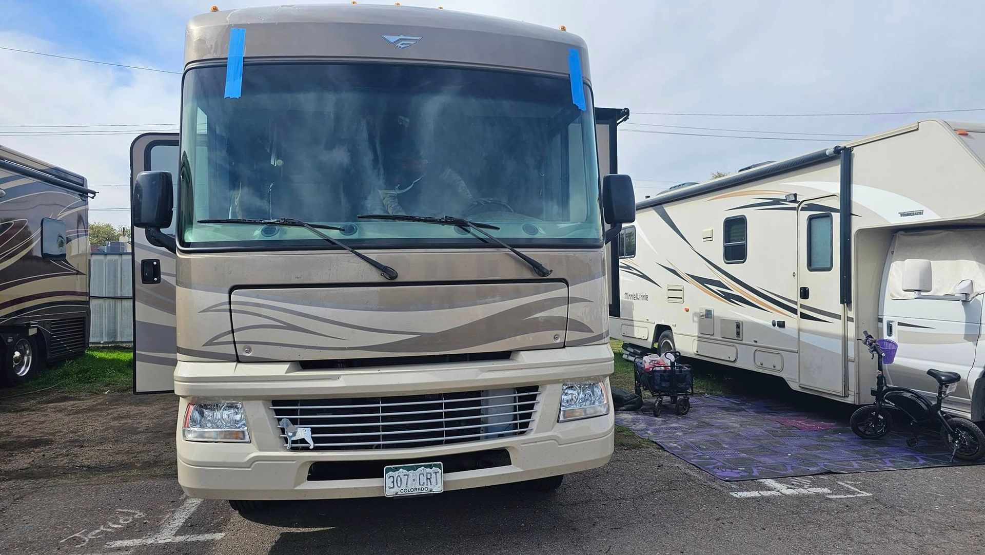 A large rv is parked in a parking lot next to other rvs.