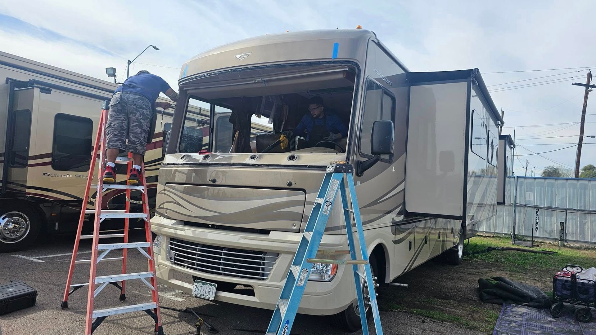 A man is standing on a ladder in front of a rv.