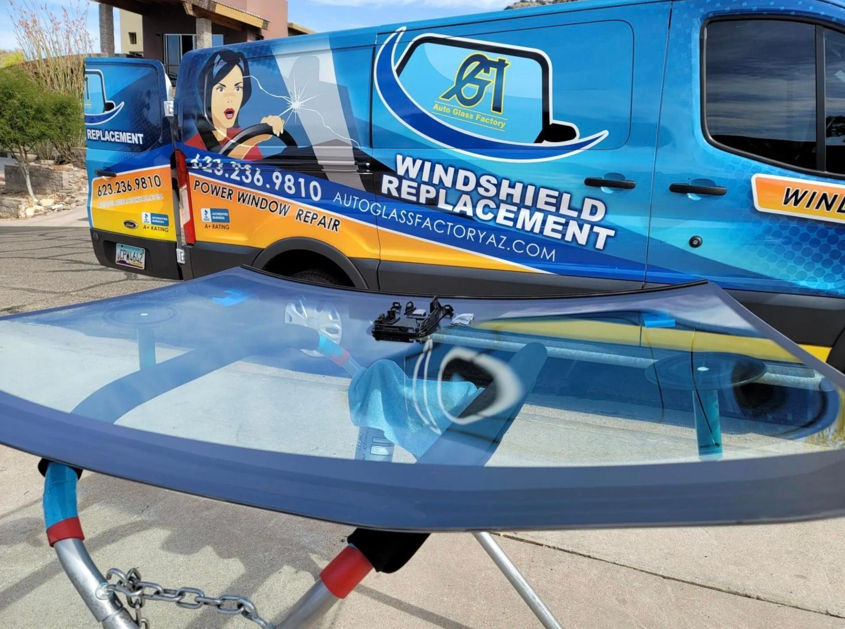 A windshield replacement van is parked next to a windshield on a stand.