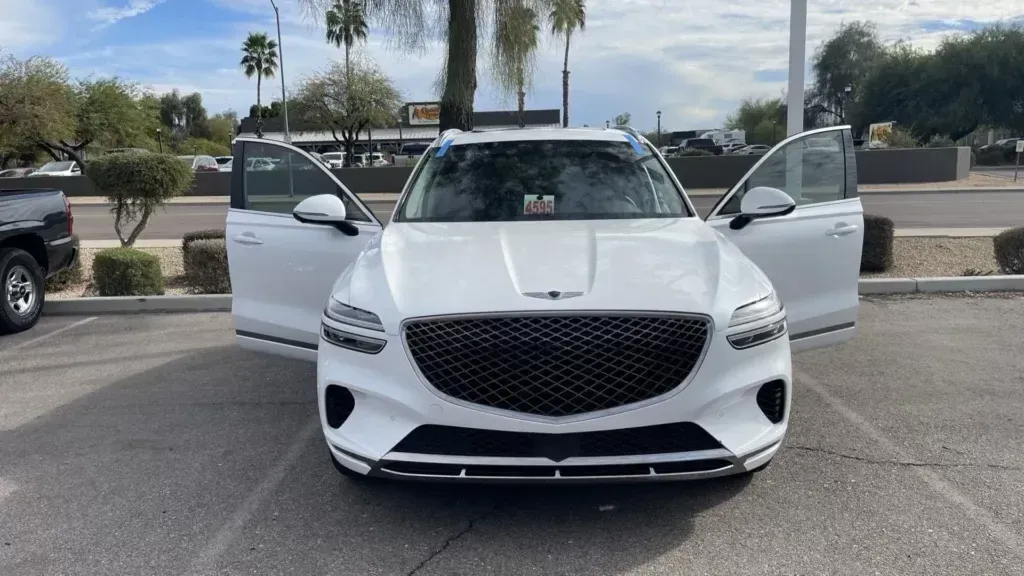 A white car is parked in a parking lot with its doors open.