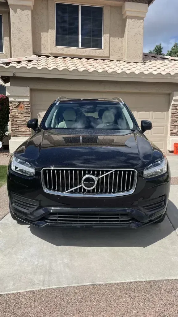 A black volvo xc90 is parked in front of a house.