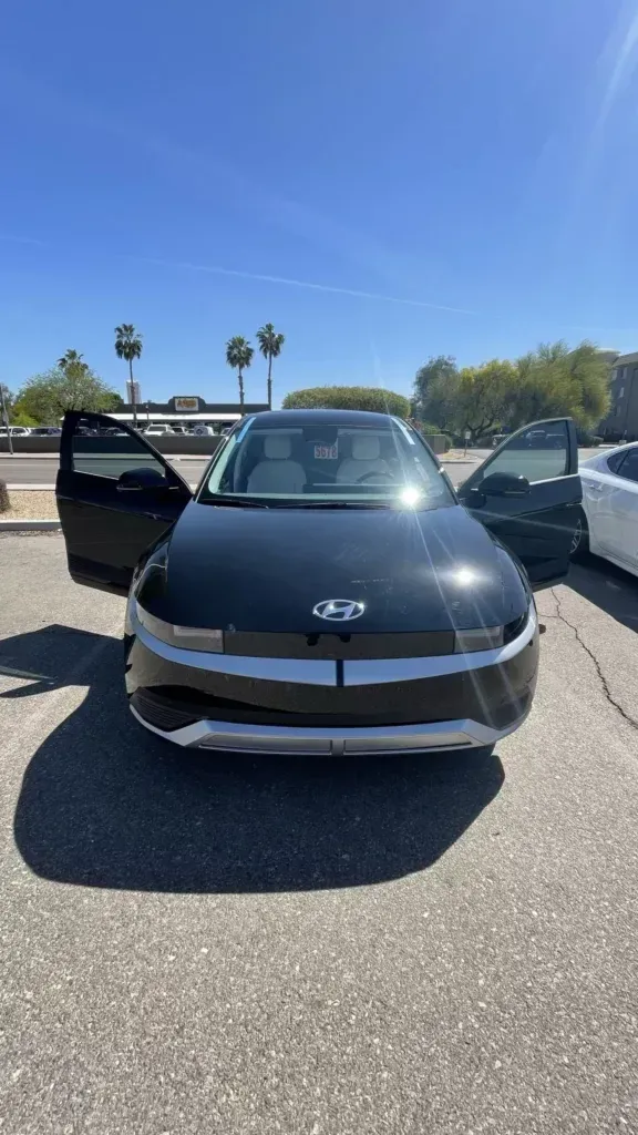 A black hyundai ioniq 5 is parked in a parking lot with its doors open.