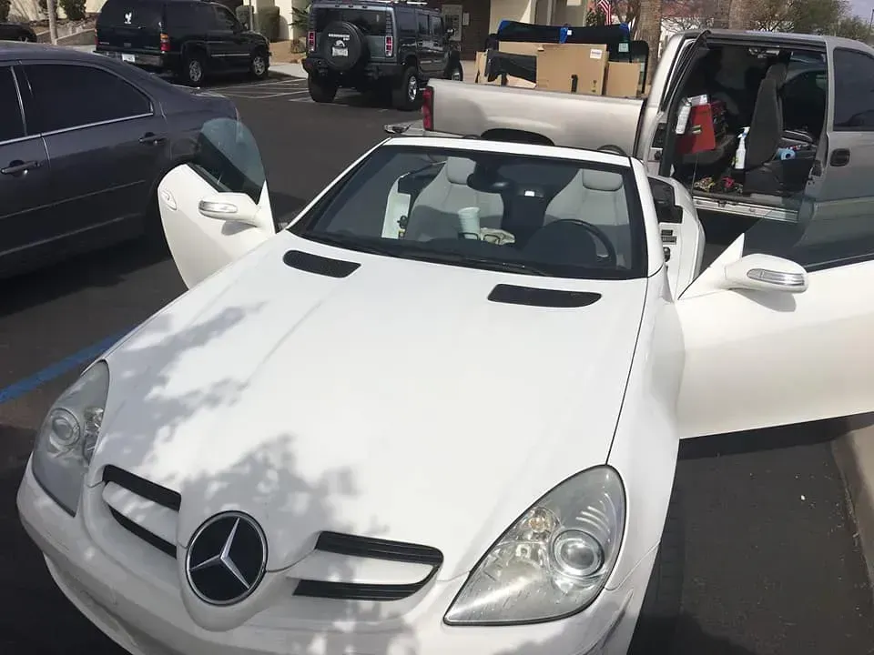 A white mercedes is parked in a parking lot with its doors open