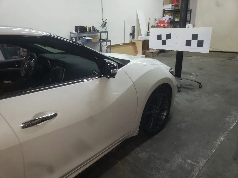 A white car is parked in a garage next to a checkered sign