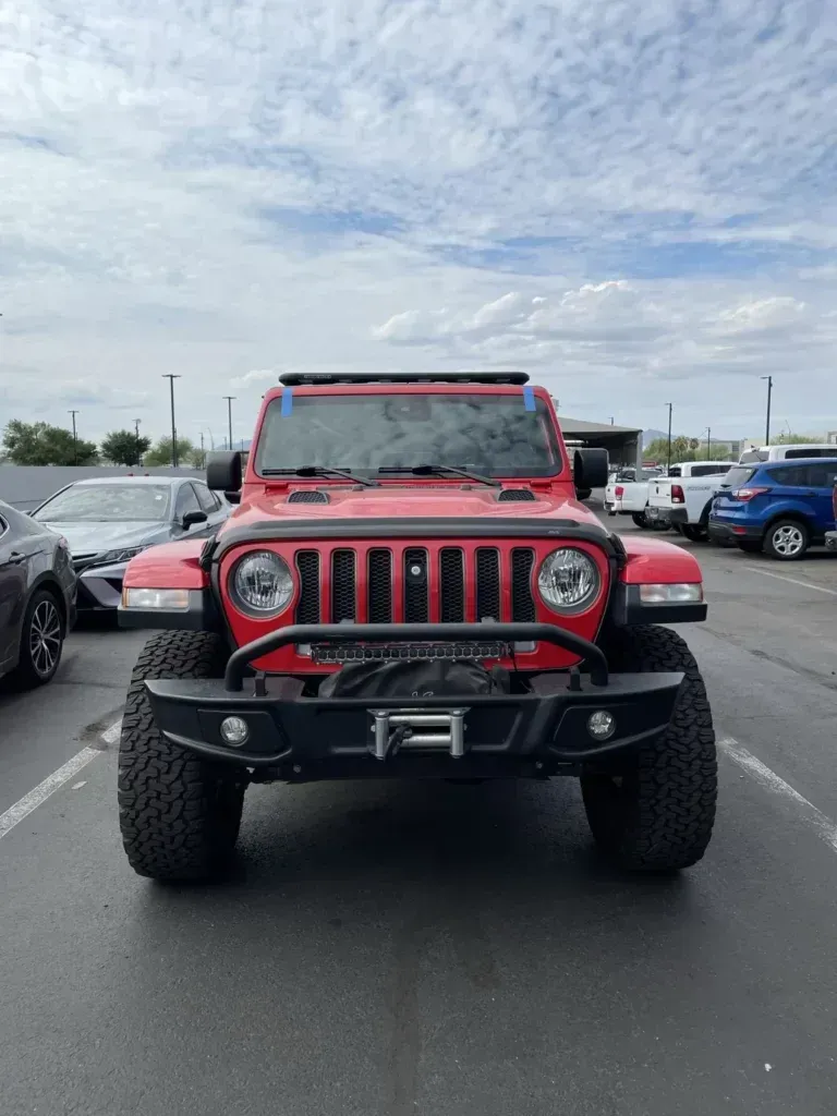 A red jeep is parked in a parking lot.