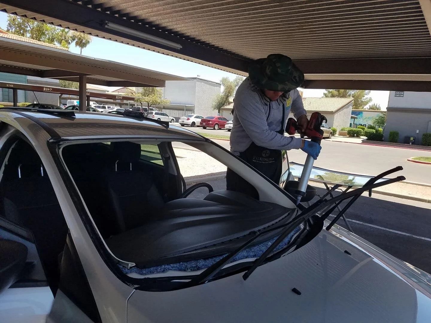 A man is installing a windshield on a white car