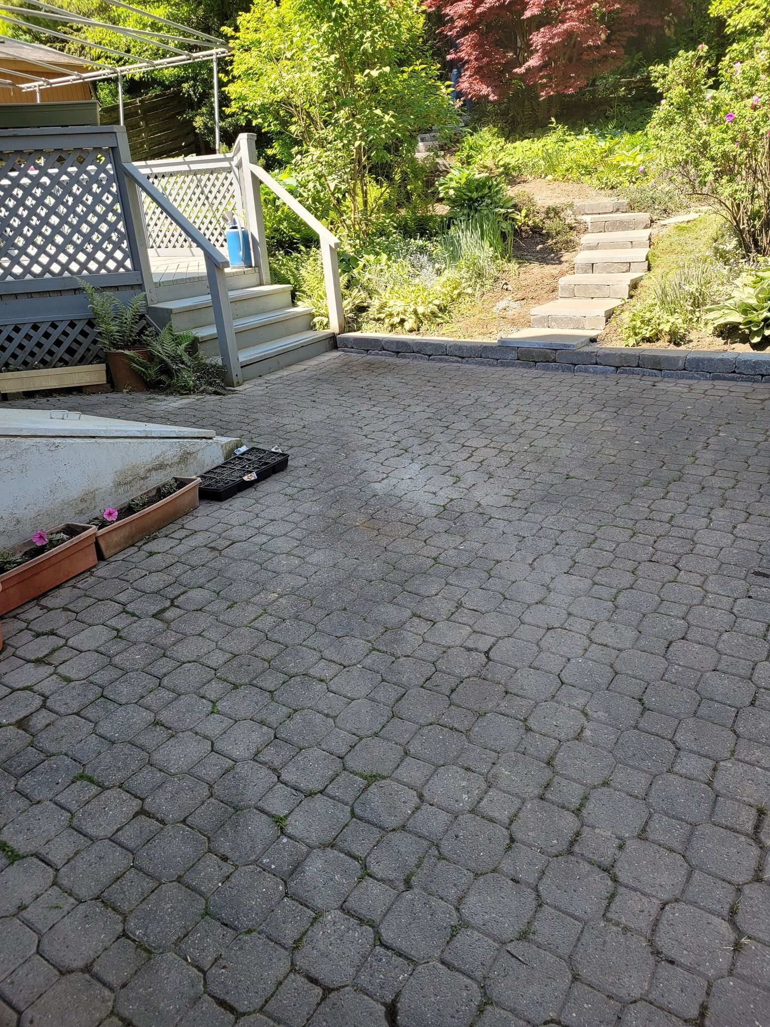 A brick patio with a staircase leading up to a deck.
