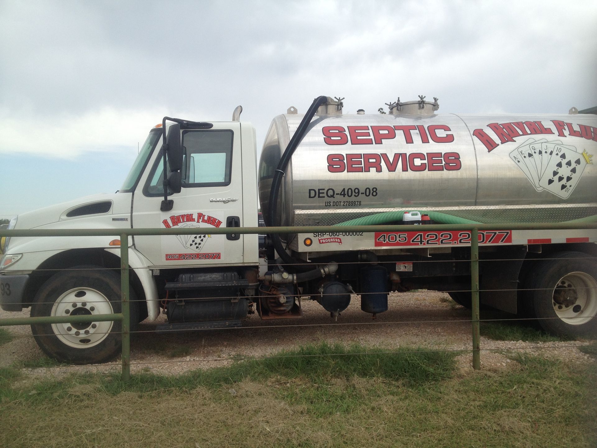White septic service truck with a large tank, parked outdoors, under a cloudy sky.